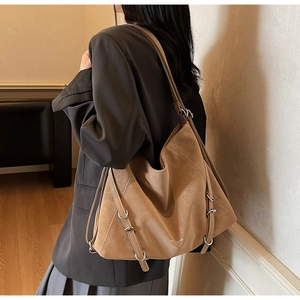 Detail view of large camel tote bag showing silver side buckles and soft matte leather texture
