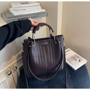 Detail of dark brown woven handbag showing intricate texture and gold metal ring buckles