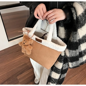 Detail of faux suede tote bag with white faux shearling trim and cute plush bear charm