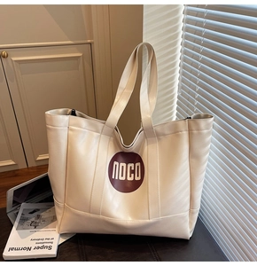 Detail of off-white PU leather tote bag featuring a purple circular NOCO logo print