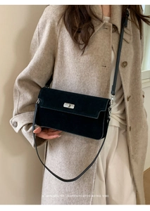 Close-up of matte black suede crossbody bag with silver rectangular turn-lock detail