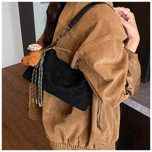 Détail du sac dumpling en daim noir avec un charme d'ours en peluche et corde tressée
