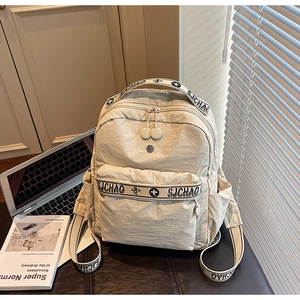 Detail of cream pleated nylon backpack showing texture, dual zippers, and SJCHAO straps