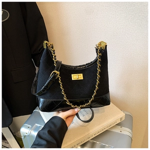 Detail of black quilted hobo bag with gold metal chain strap and twist lock on books
