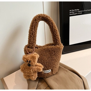 Détail d'un sac cabas en peluche marron avec breloque ours et étiquette tissée devant