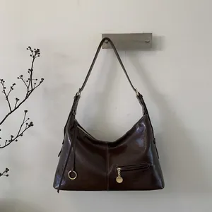 Detail of dark brown oil wax leather bag with glossy finish and gold metal zipper