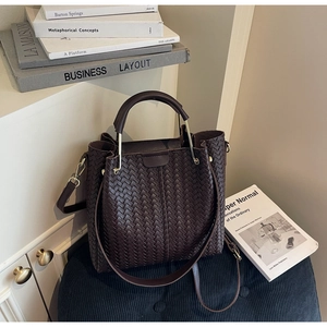 Detailed close-up of dark brown woven tote bag with round metal handle and PU leather texture
