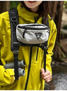 Nahaufnahme der hellgrauen Karo-Brusttasche mit Sueptly-Logo auf gelber Outdoorjacke