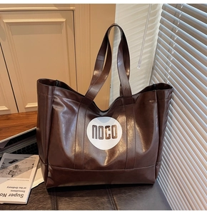 Macro shot of the dark brown glossy leather tote bag showing high-end texture and logo detail
