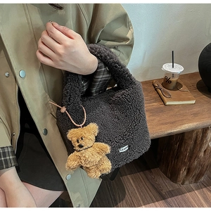 Détail du sac seau en peluche marron foncé avec breloque ours et étiquette tissée au café