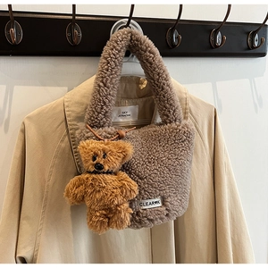 Détail du sac seau en peluche avec étiquette de marque et breloque ours assortie sur un manteau