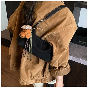 Détail du sac dumpling en daim noir avec breloque chien en peluche et boucles argent