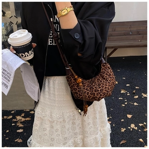 Close-up of leopard print crescent bag with wooden bead tassels in outdoor scenery