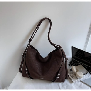Detail of vintage brown suede tote bag with silver metallic rings and adjustable strap
