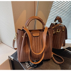 Close-up of caramel brown woven leather bucket bag with gold hardware and top handles