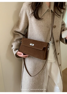 Detail of a dark brown suede crossbody bag with silver twist lock and minimalist retro vibe