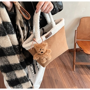 Detail of suede bucket bag with white faux shearling trim and cute brown bear charm