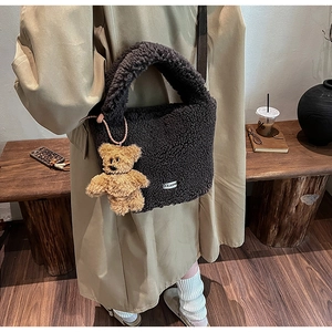 Détail du sac seau en peluche marron foncé avec pendentif ours et étiquette tissée