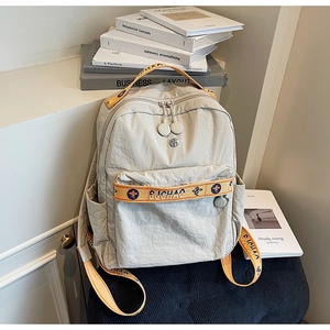 Detail of grey nylon backpack featuring orange woven straps and multi-pocket design