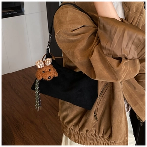 Détail du sac à bandoulière noir avec pendentif chien en peluche marron et boucle en métal