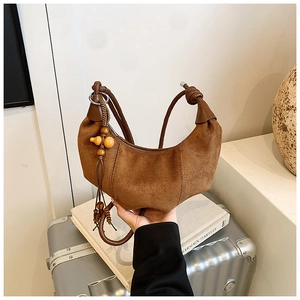 Detailed macro view of a vintage brown suede hobo bag with ethnic wooden bead charm detail