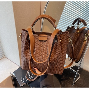 Detail of dark brown woven tote bag with metallic ring handle and crossbody strap