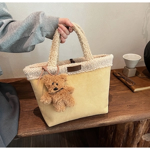 Detail of faux shearling and suede tote bag with a cute plush bear charm accessory