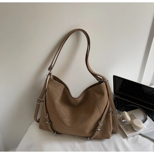 Detail of a brown leather tote bag with silver hardware buckles and shoulder straps