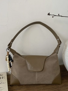 Retro khaki suede and leather hobo bag with ethnic beads on a rustic wooden table