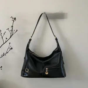 Close-up of black glossy leather bag with golden zipper and metallic hardware details