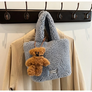 Détail d'un sac seau en peluche bleue avec charm ours brun et étiquette blanche