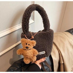 Gros plan d'un sac seau en laine d'agneau marron foncé avec un pendentif ours peluche