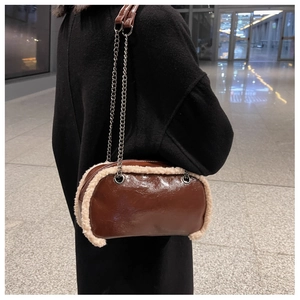 Close-up of brown glossy shoulder bag with cream faux fur trim and silver chain strap