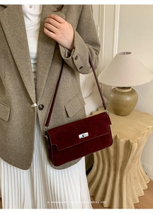 Detail of vintage burgundy suede shoulder bag with silver turn-lock and leather strap