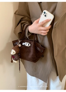 Detail of vintage suede bucket bag with silver clasp and a cute brown bear charm accessory