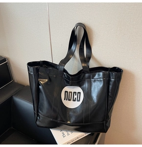 Detail of a black high-shine tote bag with white noco logo on a leather seat