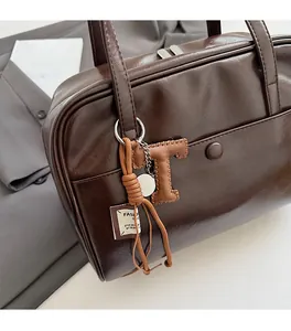 Close-up of retro dark brown leather tote bag with a fashion letter T keychain charm