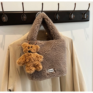 Détail du sac seau marron foncé en peluche avec breloque ours et étiquette de marque