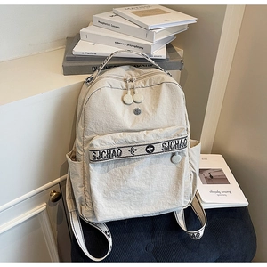 Detail of beige nylon backpack showing adjustable straps and SJCHAO letter branding