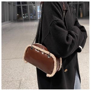 Detail of dark brown glossy crossbody bag with faux shearling trim and metal chain strap