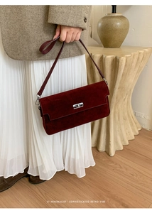 Detail of dark burgundy frosted suede crossbody bag with silver twist lock and strap