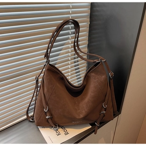 Brown vintage hobo tote bag with dual straps placed by a sunlit shutter window