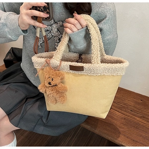 Detailed shot of yellow suede tote bag with teddy fleece trim and cute bear charm