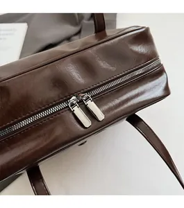 Detail of smooth metal double zipper closure on dark brown polished faux leather bag