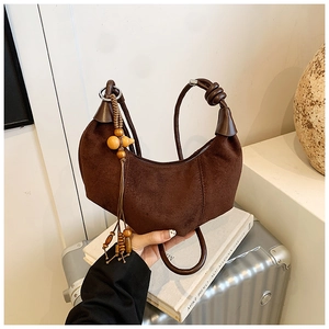 Detail of dark brown suede hobo bag featuring a decorative wooden bead charm and knotted handle