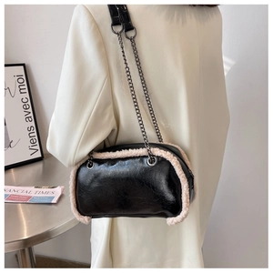 Detail view of black patent leather bag with white shearling trim and dual chain straps