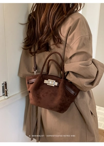 Detail of dark brown suede handbag featuring silver lock buckle and retro minimalist design