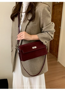 Detailed close-up of dark red suede crossbody bag with elegant silver metallic twist lock
