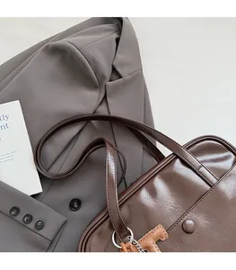Detail of dark brown vintage faux leather hobo bag with cute horse charm and round buckle