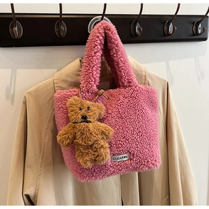 Détail d'un sac seau rose en polaire avec charm ours en peluche et étiquette tissée